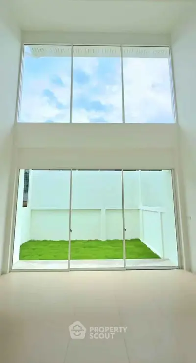 Spacious modern living room with floor-to-ceiling windows and private garden view.