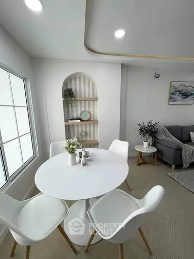 Modern living room with stylish dining area and cozy seating, featuring elegant decor and natural light.