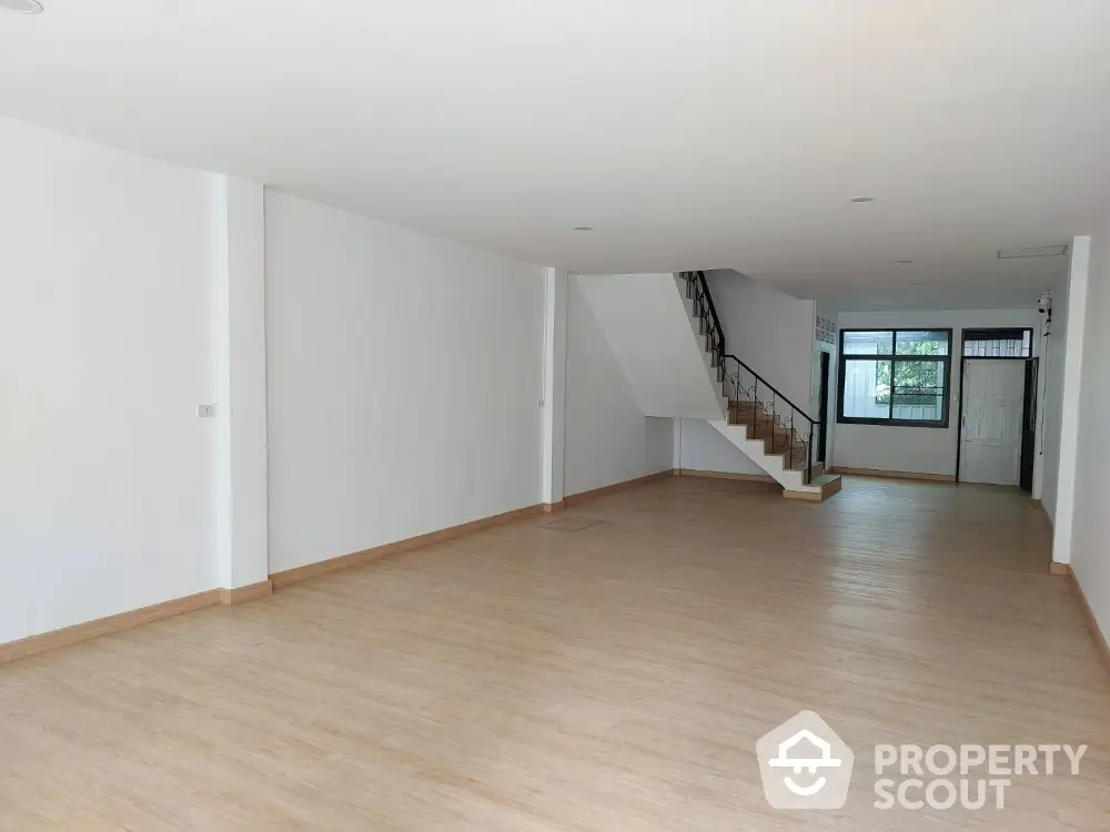 Spacious open-plan living area with wooden flooring and staircase