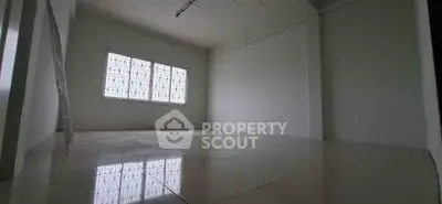 Spacious empty room with tiled flooring and large window, ideal for customization.