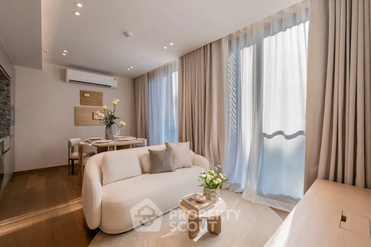 Elegant living room with modern decor, large windows, and cozy seating area in a stylish apartment.
