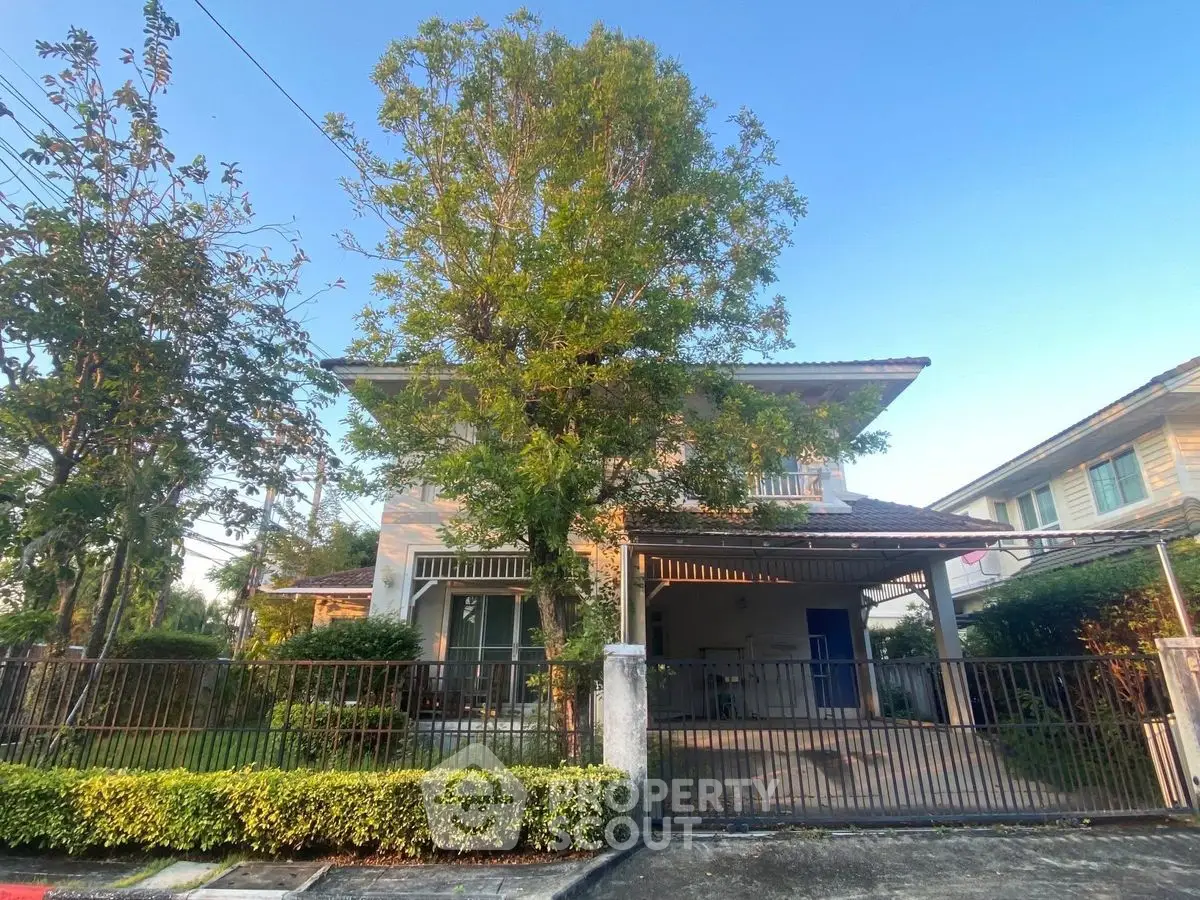 Charming two-story house with lush greenery and spacious front yard in serene neighborhood.