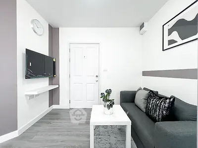 Modern living room with sleek decor and wall-mounted TV, featuring a stylish gray sofa and minimalist design.