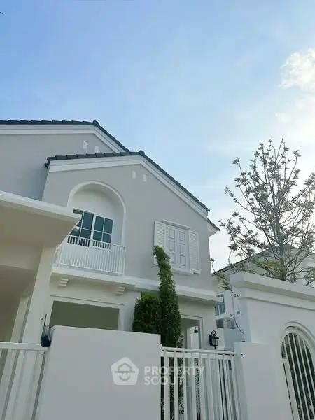 Charming two-story house with elegant balcony and modern architecture under a clear blue sky.
