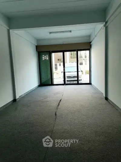 Spacious empty room with large glass doors and carpet flooring, ideal for office or retail space.