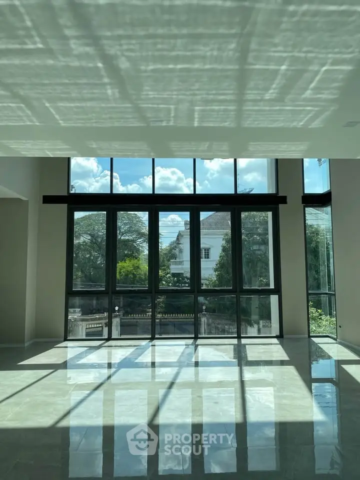 Spacious living room with floor-to-ceiling windows offering stunning natural light and garden views.