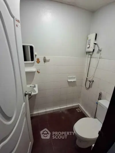 Compact bathroom with shower and toilet in a minimalist design.