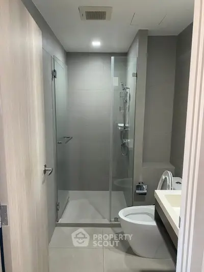 Modern bathroom with glass shower and sleek fixtures in contemporary apartment.