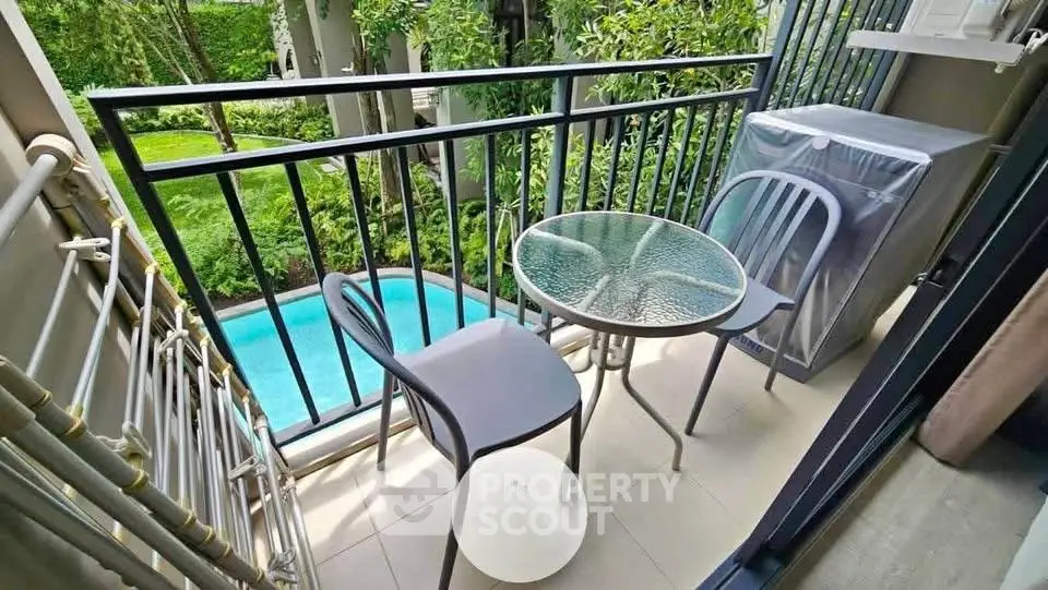 Charming balcony with pool view, featuring a glass table and chairs, perfect for relaxation.
