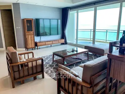 Luxurious living room with ocean view, modern furniture, and large windows opening to a spacious balcony.