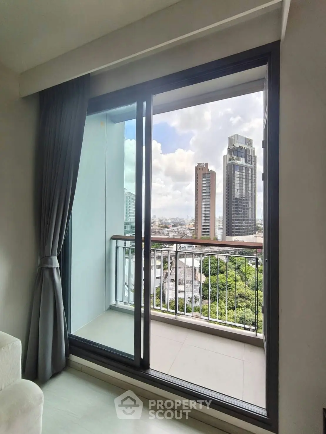 Stunning city view from modern apartment balcony with floor-to-ceiling glass doors.