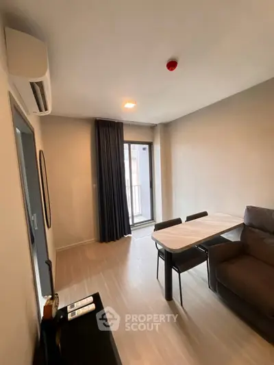 Modern living room with balcony access, featuring sleek furniture and natural light.