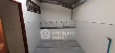 Spacious utility area with sink and tiled flooring, ideal for laundry or storage.