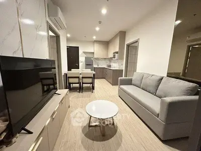 Modern living room with open kitchen layout, stylish furniture, and sleek design.