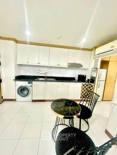 Modern kitchen with sleek cabinets, washing machine, and stylish dining set
