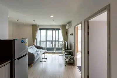 Bright modern living room with balcony and city view, featuring sleek furniture and natural light.