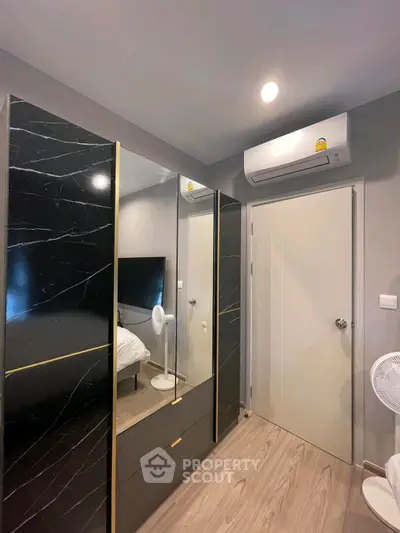 Modern bedroom with sleek black wardrobe and air conditioning unit