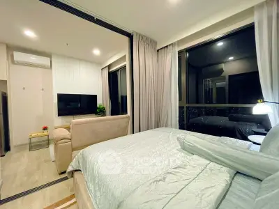 Modern studio apartment with cozy bedroom and living area, featuring large windows and stylish decor.
