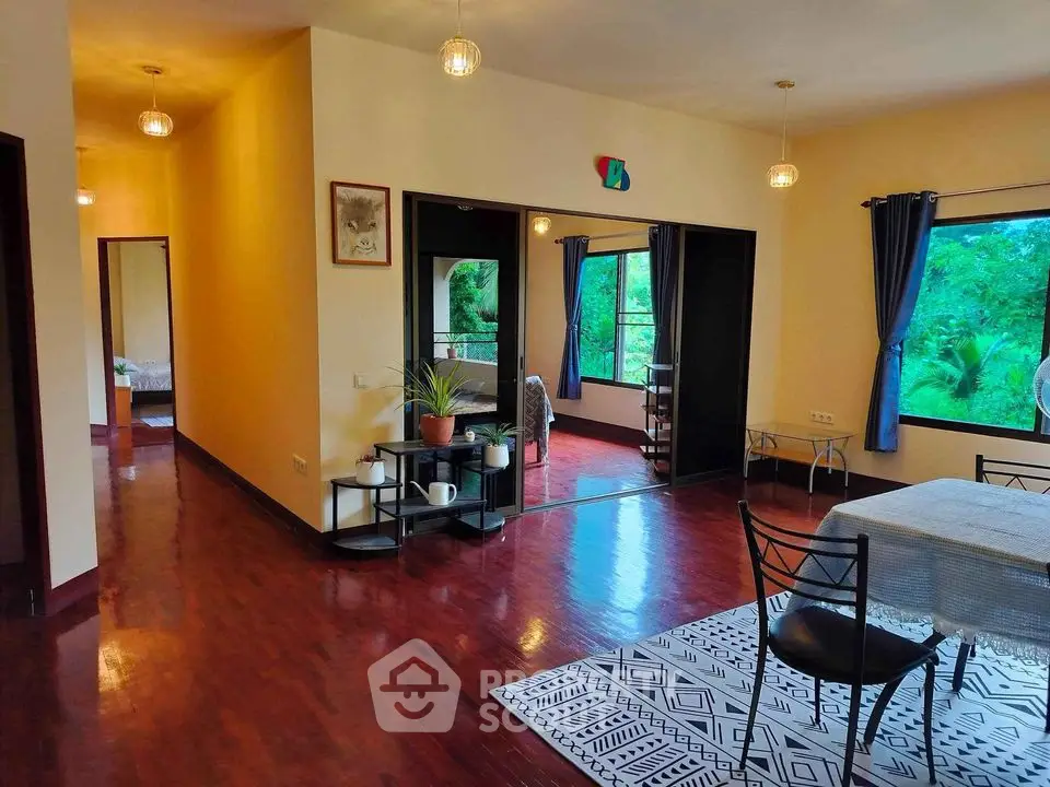 Spacious open-plan living area with dining set and lush green views