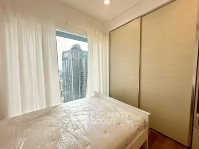 Modern bedroom with city view and large closet in high-rise apartment.