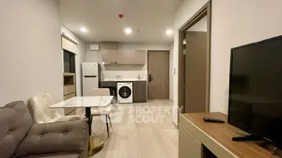 Modern apartment interior with cozy living area and kitchen featuring washing machine and fridge.