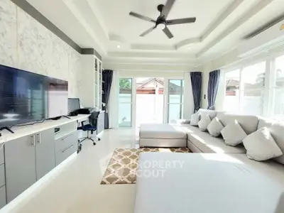 Spacious modern living room with large sectional sofa and entertainment center, featuring elegant decor and ample natural light.