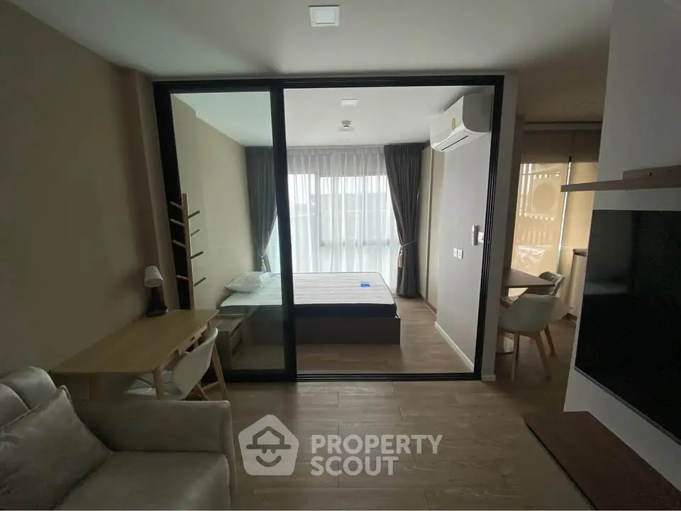 Modern studio apartment with glass partition, cozy living area, and natural light.