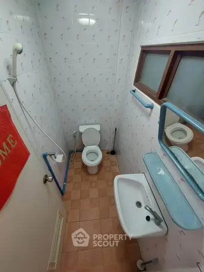 Compact bathroom with tiled walls and basic fixtures, featuring a toilet, sink, and shower area.