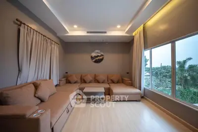 Spacious living room with modern sectional sofa and large windows offering serene garden view