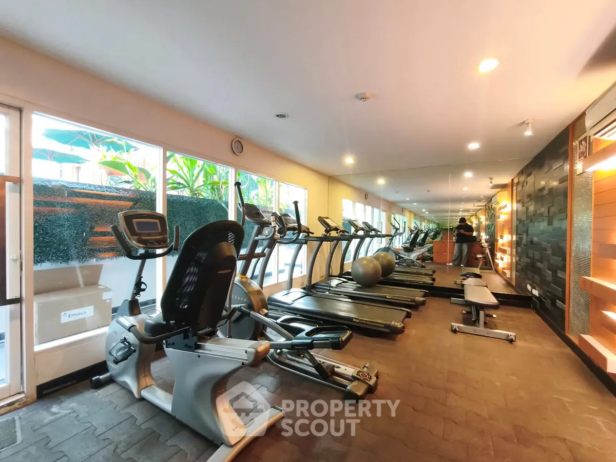 Modern gym with state-of-the-art equipment and large windows for natural light.