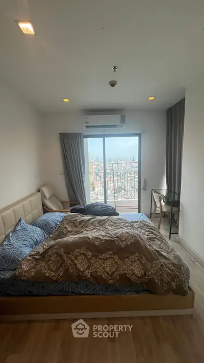 Spacious bedroom with city view and balcony access, featuring modern decor and natural light.