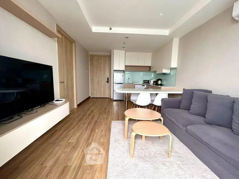 Modern open-plan living room with sleek kitchen and cozy seating area, perfect for urban living.