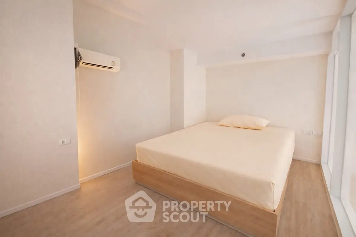 Minimalist bedroom with wooden flooring and air conditioning