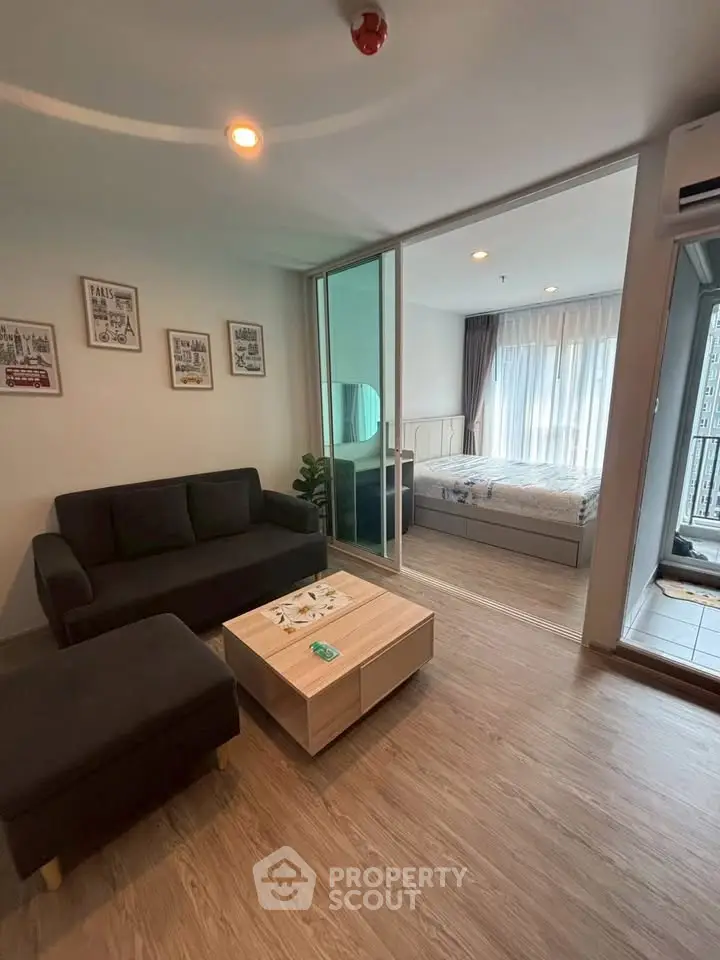Modern living room with cozy sofa and sliding glass doors leading to a bright bedroom.