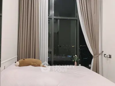 Cozy bedroom with city view, large window, and elegant curtains for a serene ambiance.