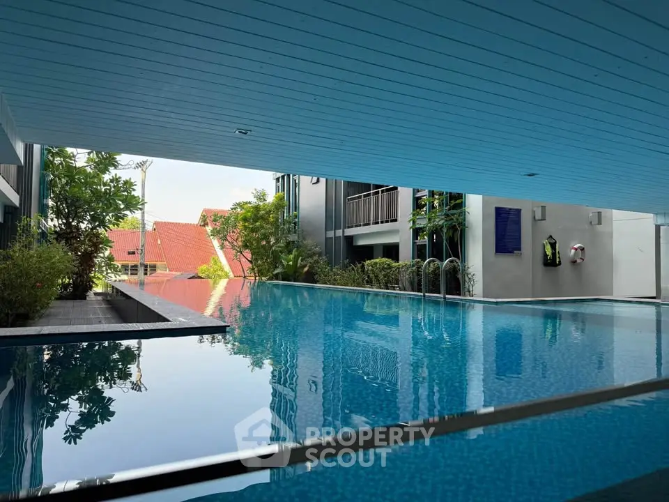 Luxurious modern pool area with serene surroundings and lush greenery in a contemporary residential complex.