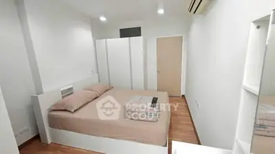 Modern minimalist bedroom with white furniture and wooden flooring