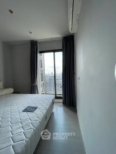 Modern bedroom with city view, featuring a large window and minimalist decor.