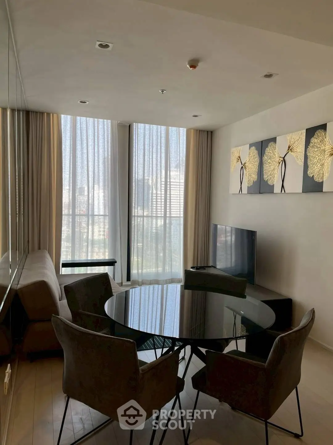 Modern living room with stylish decor, large windows, and a sleek dining area in a high-rise apartment.