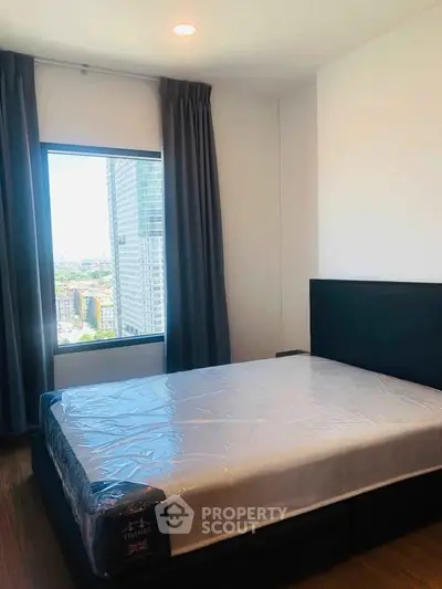 Modern bedroom with large window offering stunning city views in a high-rise apartment.