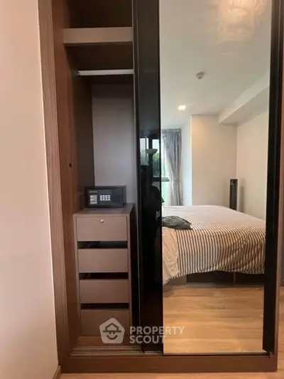 Modern bedroom with mirrored wardrobe and secure safe, featuring stylish decor and natural light.