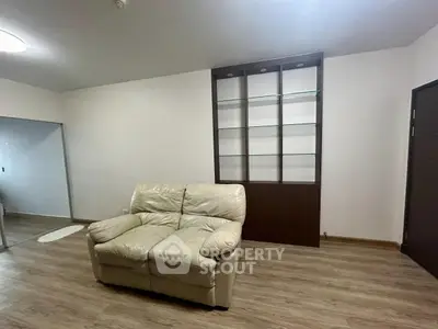 Spacious living room with cozy leather sofa and modern shelving unit.
