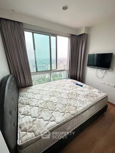 Cozy bedroom with city view, featuring a large window and wall-mounted TV.