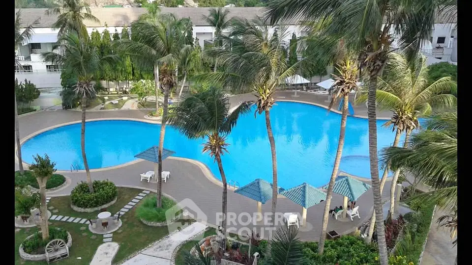 Luxurious resort-style pool area with palm trees and lounging spaces in a modern residential complex.