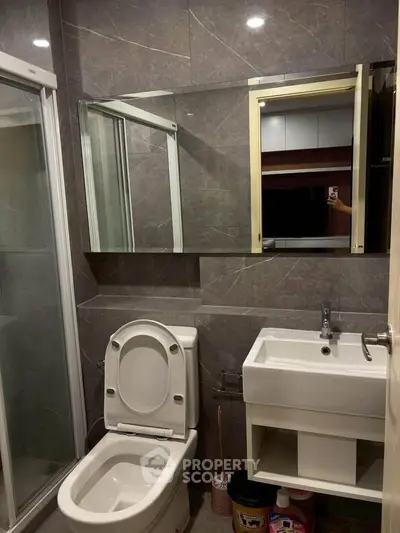 Modern bathroom with sleek design, featuring a shower, toilet, and stylish sink in a compact space.