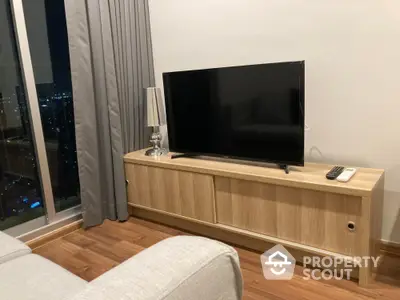 Modern living room with sleek TV setup and city view, featuring elegant wooden flooring and stylish decor.