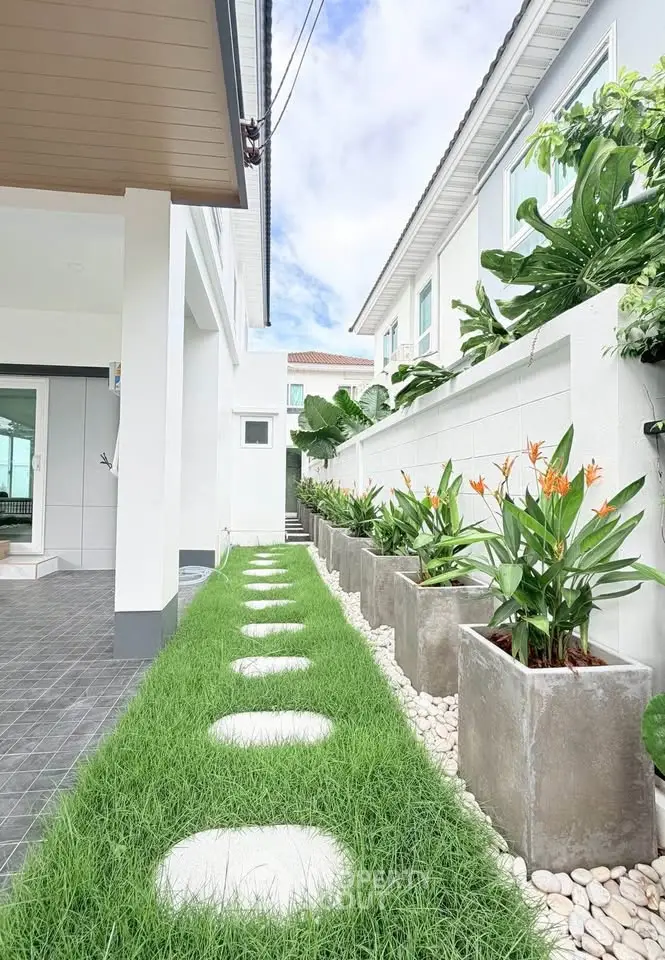 Modern home exterior with lush garden and stepping stones, showcasing contemporary design and greenery.
