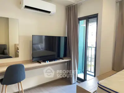 Modern bedroom with TV, desk, and balcony access in stylish apartment.