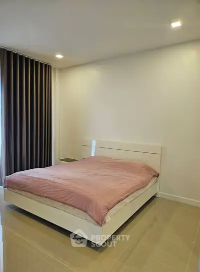 Spacious bedroom with modern design and elegant lighting, featuring a cozy bed and stylish curtains.