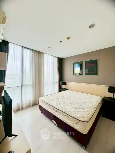 Spacious bedroom with large windows and modern decor in a stylish apartment.